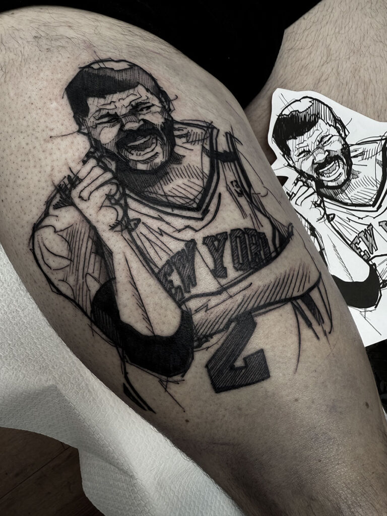 A unique black and grey forearm tattoo by Quincy of Kwillsink featuring the Pokémon Mew. The character is rendered with soft shading while holding a large, highly detailed tactical rifle, creating a contrast between "cute" and "gritty."