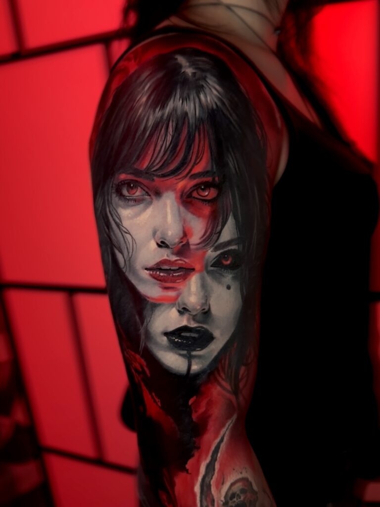 An intricate realism tattoo on an arm by Kenny from Hannon Tattoo. The piece depicts two overlapping faces with dark, gothic features and intense red eyes, set against a dark background with striking red highlights.