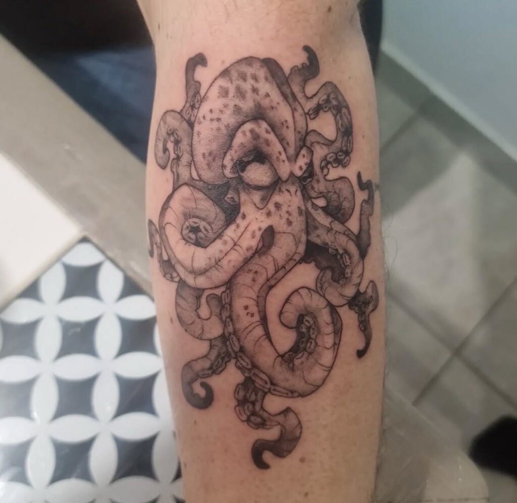 Gedetailleerde black and grey tattoo van een inktvis op een onderarm. Het ontwerp toont de textuur van de tentakels en de huid van het dier met zachte schaduwovergangen. Werk van Francois (fran6_tatoueur) op de Sint-Niklaas Tattoo Expo.