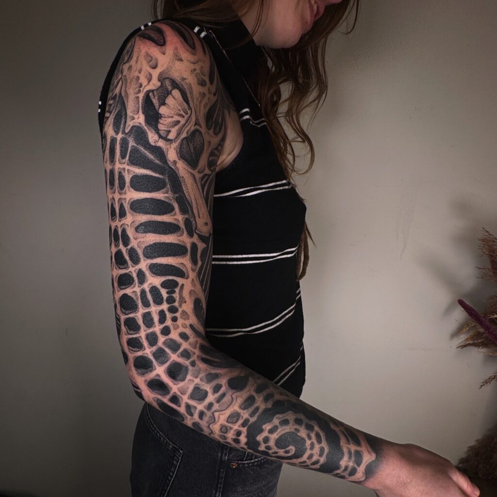 Een volledige arm-sleeve in een unieke biomorphische blackwork stijl. Het ontwerp bestaat uit complexe, organische patronen met een hoog contrast tussen diepzwarte inkt en de natuurlijke huidskleur. Werk van Simon (Sunrise Skin Art) op de Sint-Niklaas Tattoo Expo.