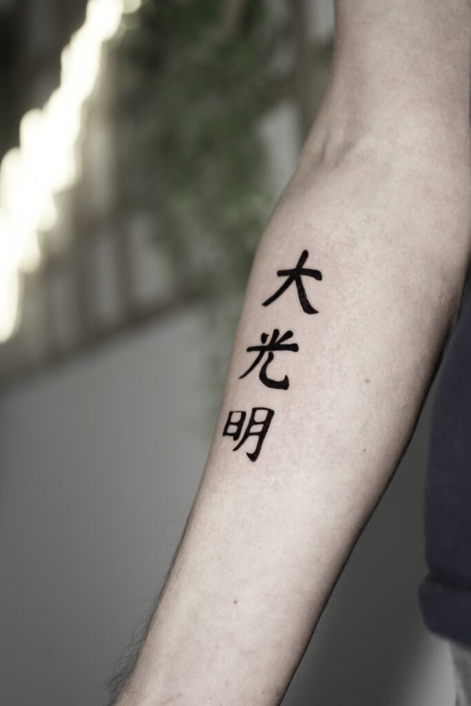 Een strakke blackwork tattoo van drie Japanse kanji-tekens op een onderarm. De tekens zijn uitgevoerd in een krachtige, kalligrafische stijl met diepzwarte inkt. Gezet door Naviia van Be Inkspired Tattoo tijdens de Sint-Niklaas Tattoo Expo.