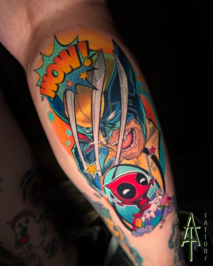 Een spectaculaire, kleurrijke comic-stijl tattoo van Wolverine die zijn klauwen toont, met een kleine Deadpool die onderaan op een eenhoorn rijdt. Het ontwerp is rijk aan actie-elementen zoals een WOW!-tekstballon en sterren. Gezet door Ayla van Ayla Tattoos tijdens de Sint-Niklaas Tattoo Expo.