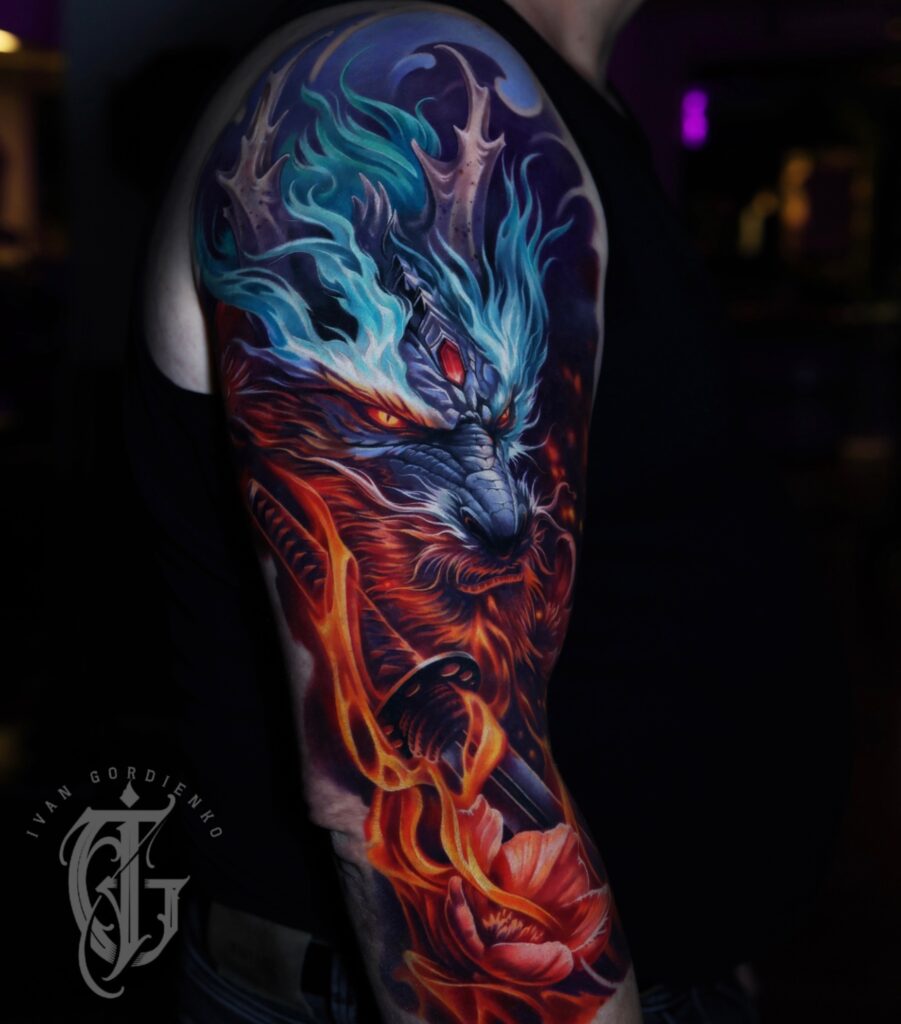 Een waanzinnig gedetailleerde full color sleeve op een bovenarm. Centraal staat een woeste draak met blauwe vlammende hoorns en gloeiende oranje ogen. De onderkant van het ontwerp wordt gedomineerd door een samoeraizwaard (katana) gehuld in realistische oranje vlammen, eindigend bij een dieprode bloem. Werk van Ivan Gordienko op de Sint-Niklaas Tattoo Expo.